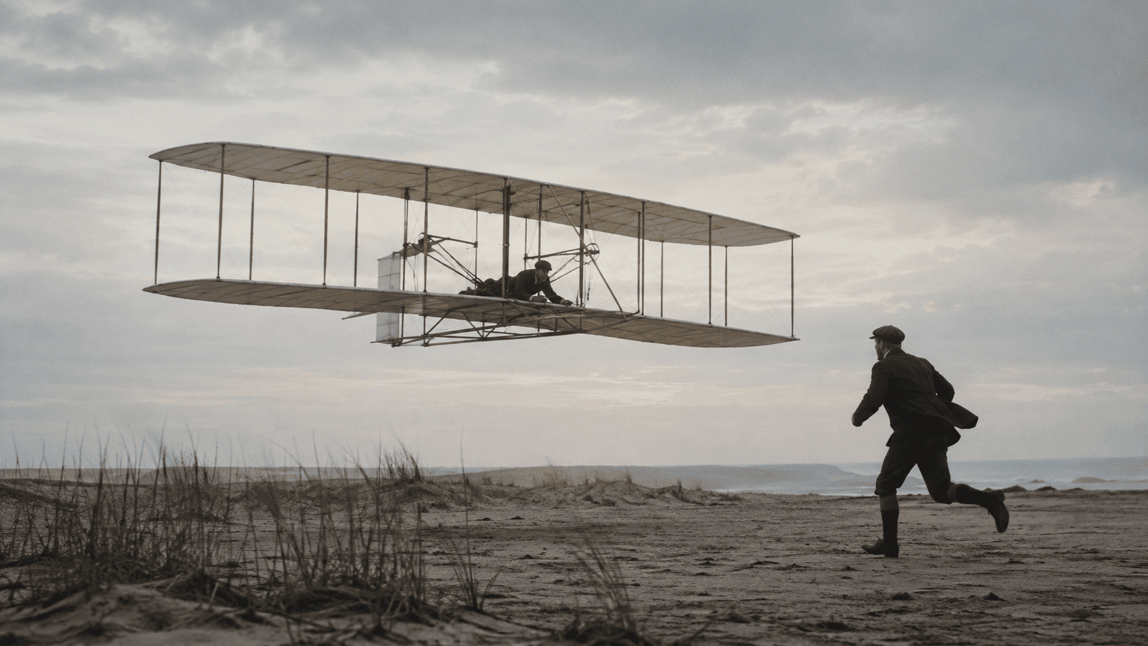 The Wright Flyer lifting from the sand at Kill Devil Hills while one brother runs beside it